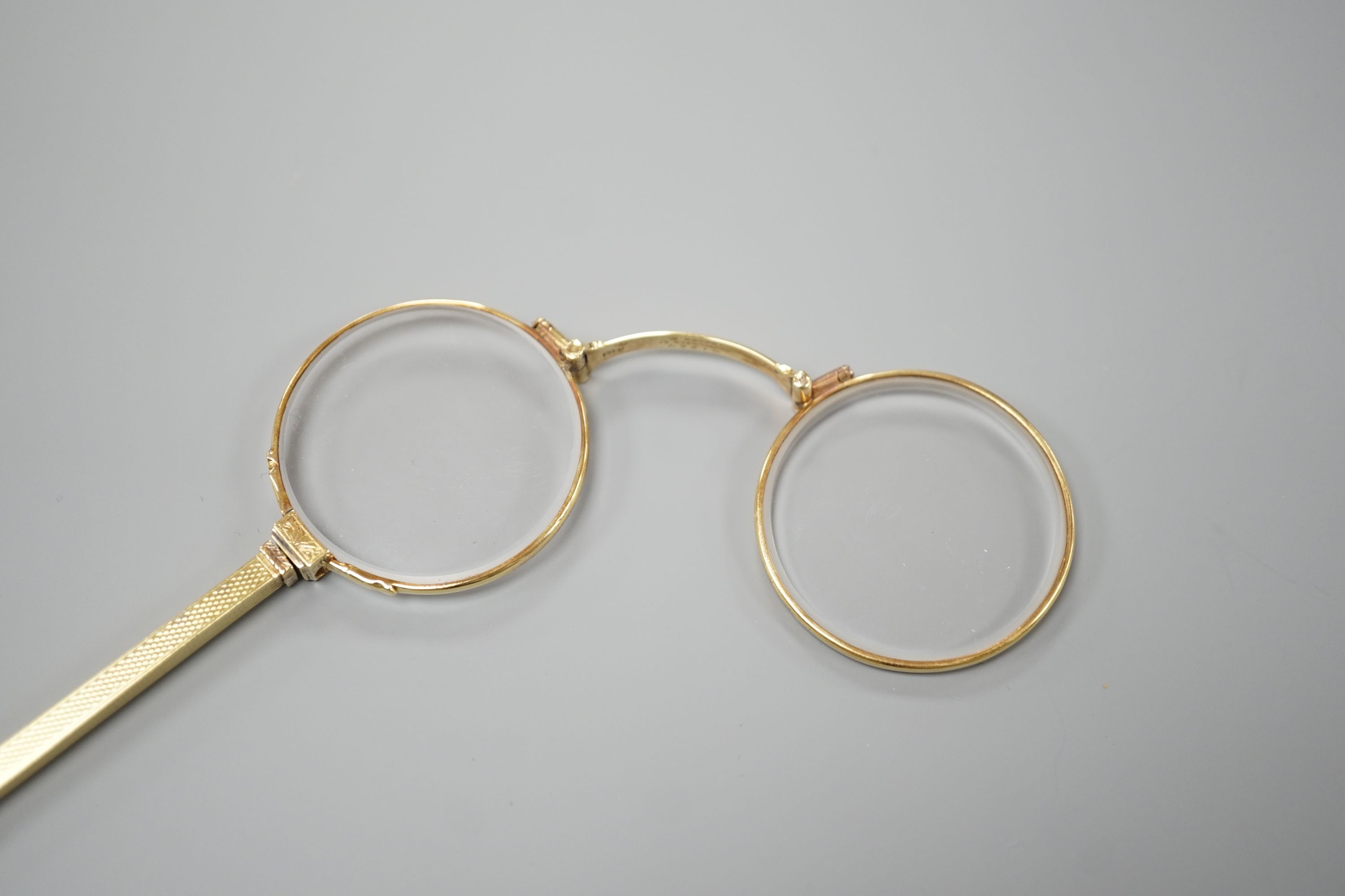 A pair of Edwardian 15ct lorgnettes, by Dixie, 20 Welbeck Street, London, with engine turned handle, 11.4cm, gross weight 28.9 grams.